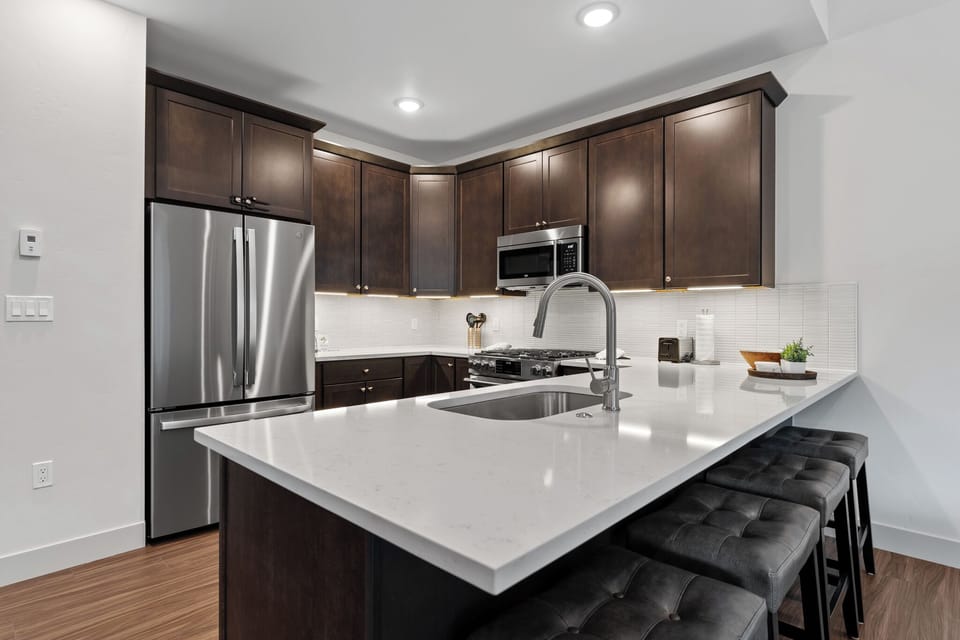 Your gourmet kitchen features rich wood cabinetry, gleaming quartz countertops, and premium stainless appliances perfect for preparing memorable meals during your stay.