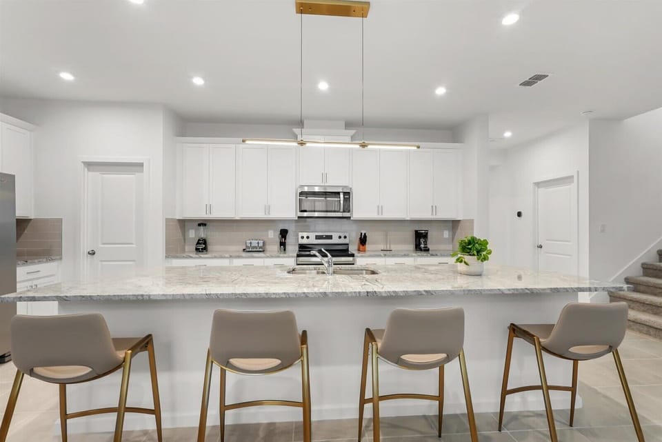 Modern kitchen with a large marble island and seating for four.
