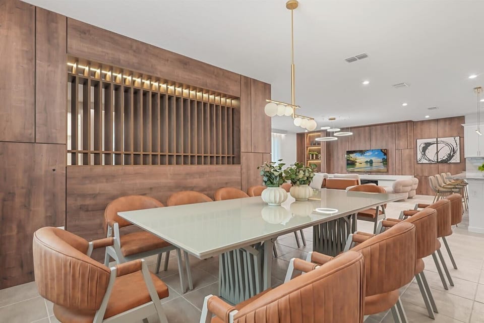 Modern dining area with leather chairs and a glass table in an open-concept living space.