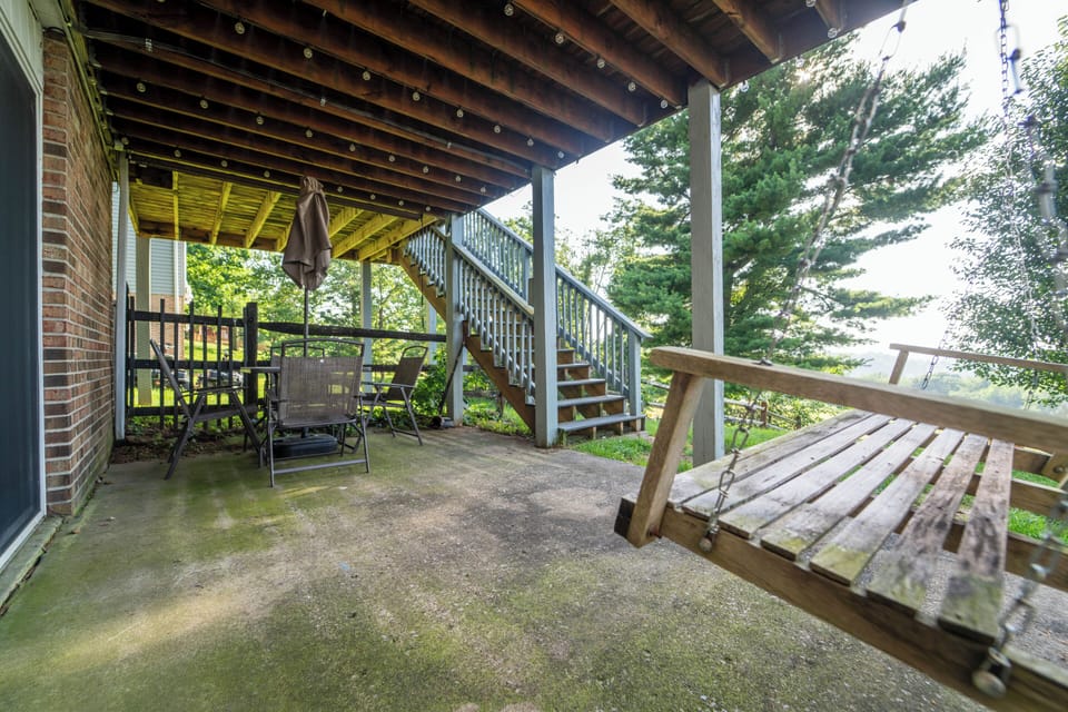 Shaded patio with porch swing, dining set, and peaceful wooded views