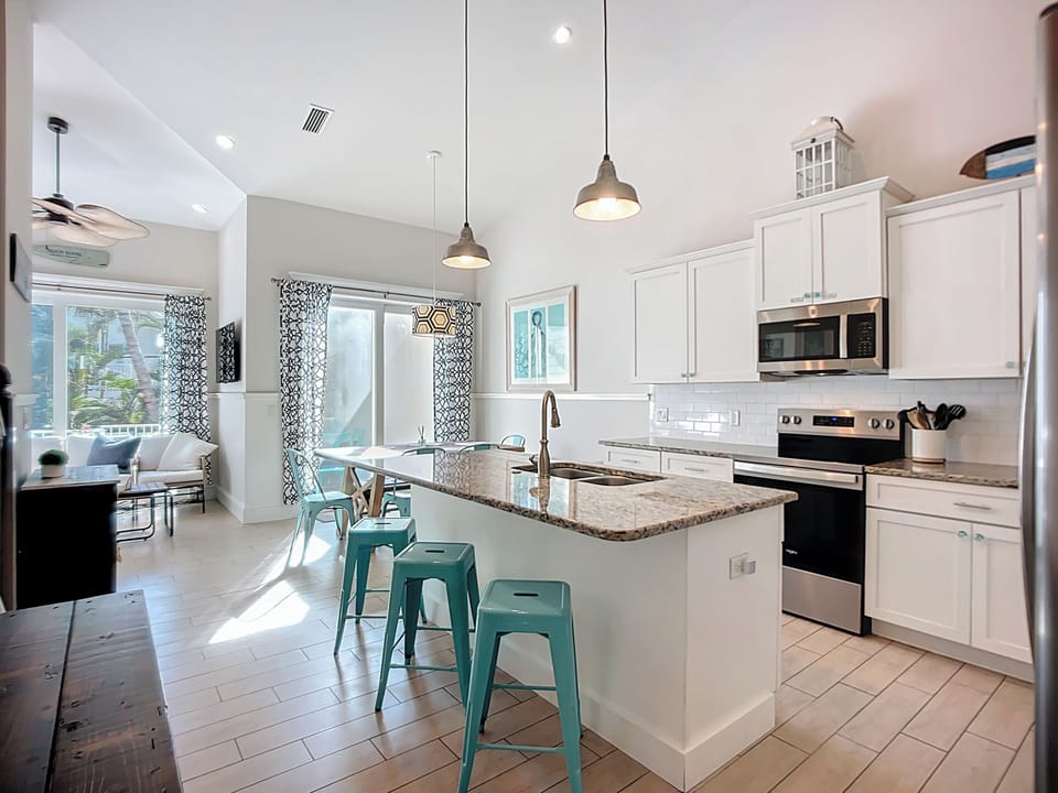 Your bright, modern kitchen invites you to create memorable meals with granite countertops, stainless steel appliances, and cheerful turquoise bar stools.