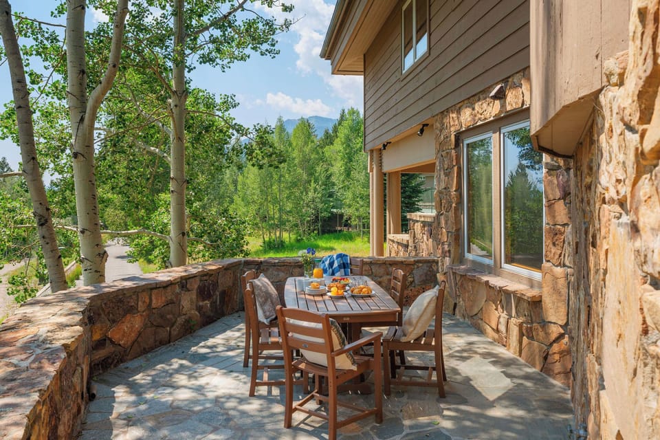 Enjoy your morning coffee at this inviting stone patio, where aspen trees and mountain vistas create a serene backdrop for your Colorado getaway.