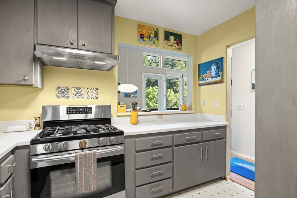 The fully equipped kitchen flows seamlessly to the indoor and outdoor dining tables, perfect for morning coffee or cooking while enjoying forest and river views.