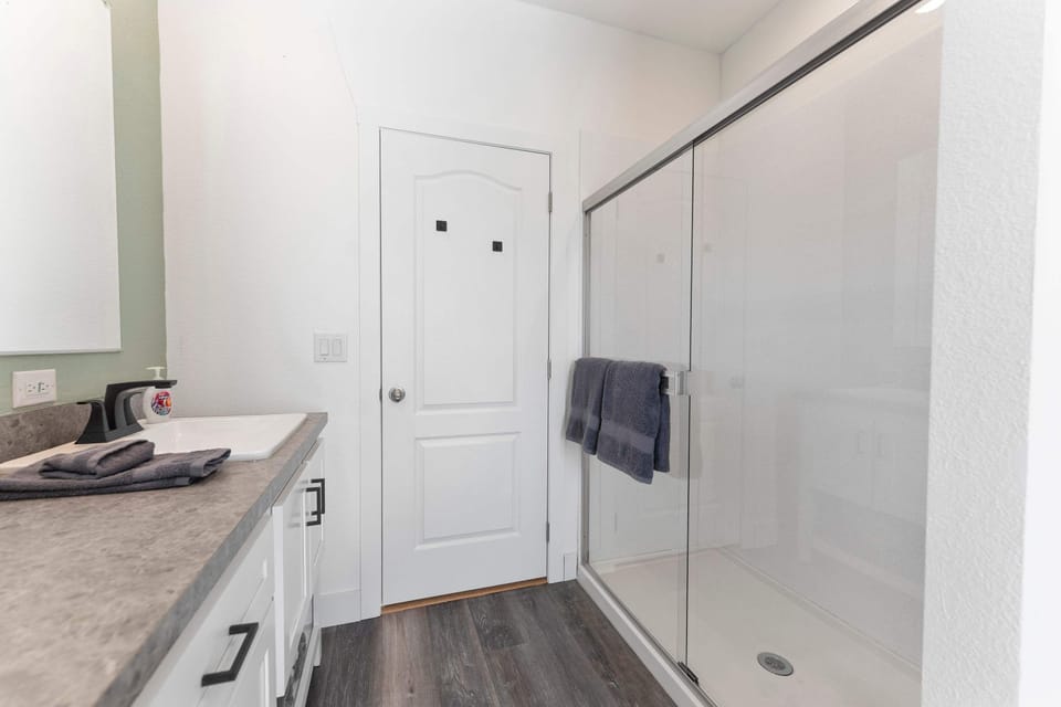 The bathroom in rhe primary suite features a double vanity and a large glass walk-in shower.