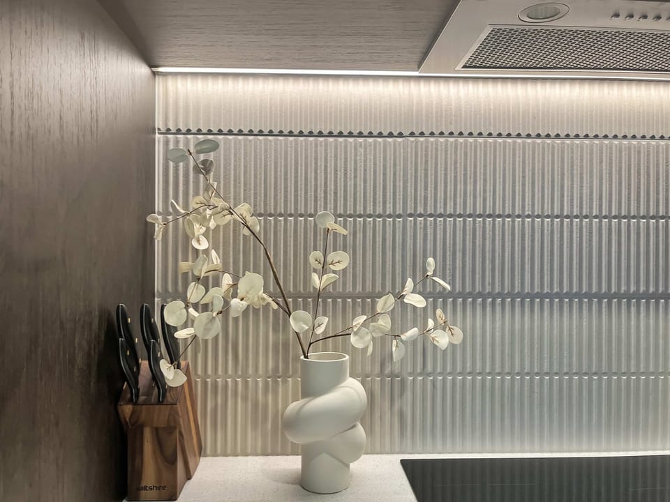 Elegant kitchen styling with textured splash back and warm lighting