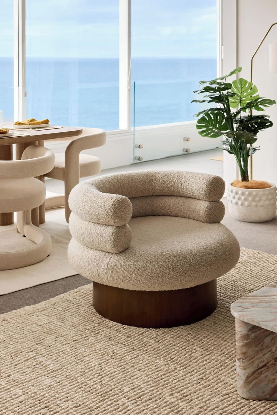 Cozy designer lounge chair set against breathtaking ocean views and soft natural tones.