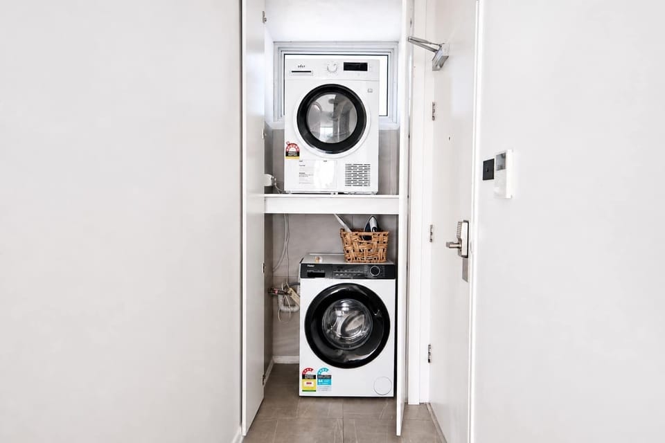 Compact Euro-Style Laundry

A smart, space-saving laundry cupboard featuring vertically stacked front-loading appliances, neutral tiling, and crisp white bi-fold doors for a seamless minimalist look.