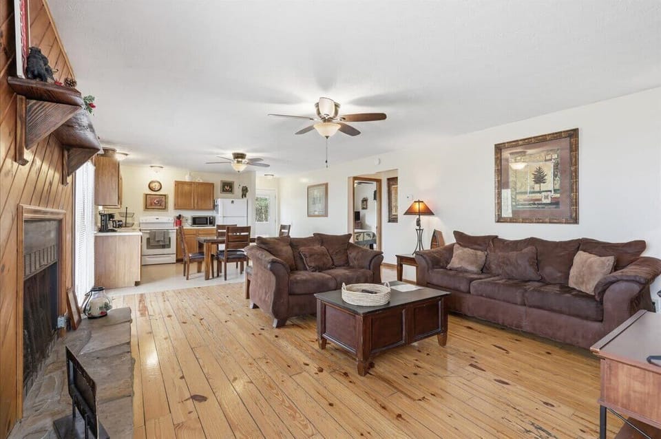 Relax in your spacious living room with plush seating, rustic wood floors, and cozy fireplace creating the perfect mountain retreat atmosphere.