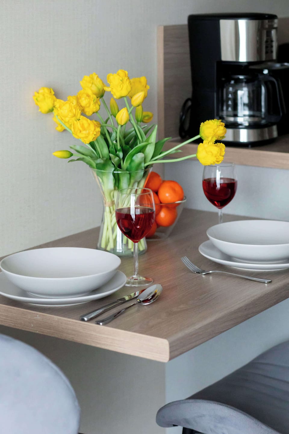 A small dining table with a vase of flowers, cups, and breakfast items, ready for use. It creates a welcoming dining corner.