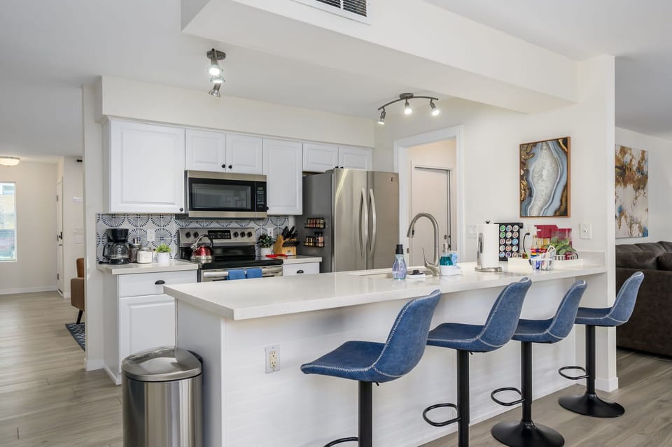 Fully equipped kitchen with stainless steel appliances and bar seating.