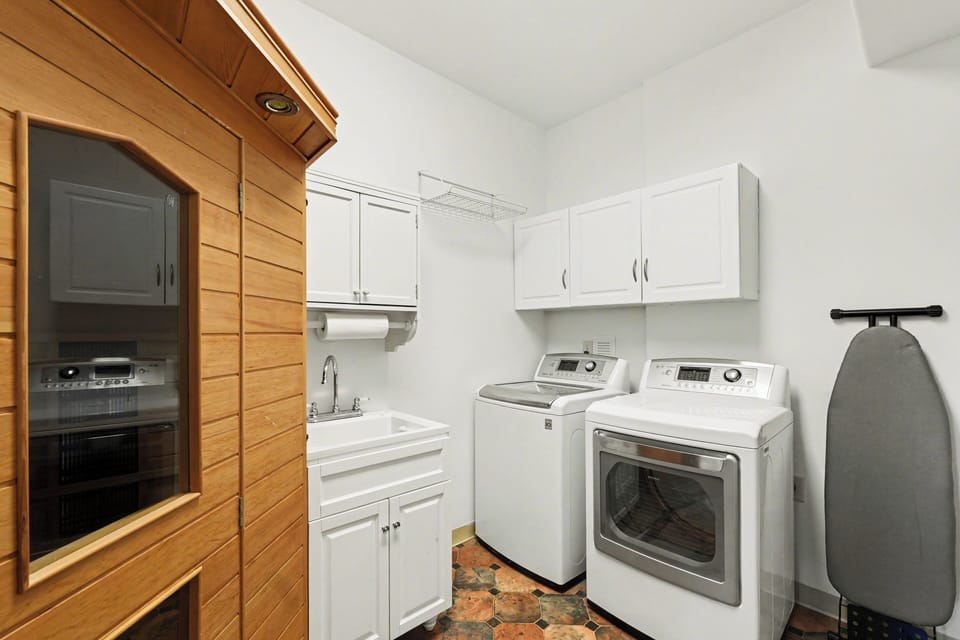 Full laundry with washer/dryer, sink, storage—plus a private sauna