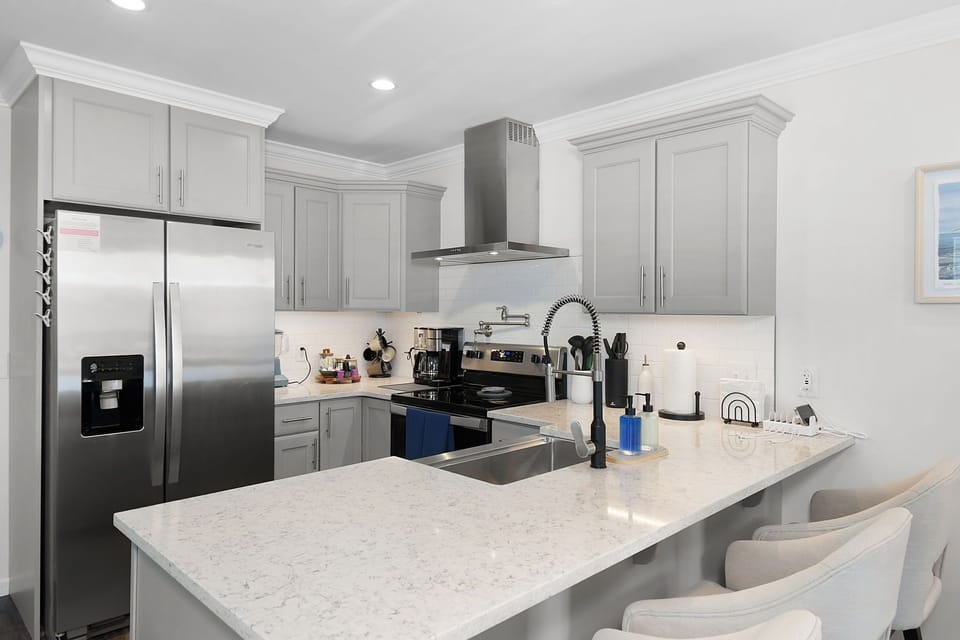 Fully stocked coastal kitchen with stainless steel appliances and quartz counter