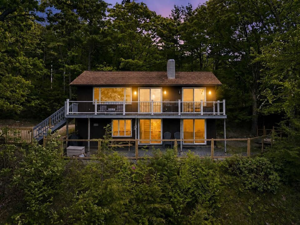 Twilight is when this mountain retreat truly shines, combining cozy cabin charm with the tranquility of the Lakes Region forest.