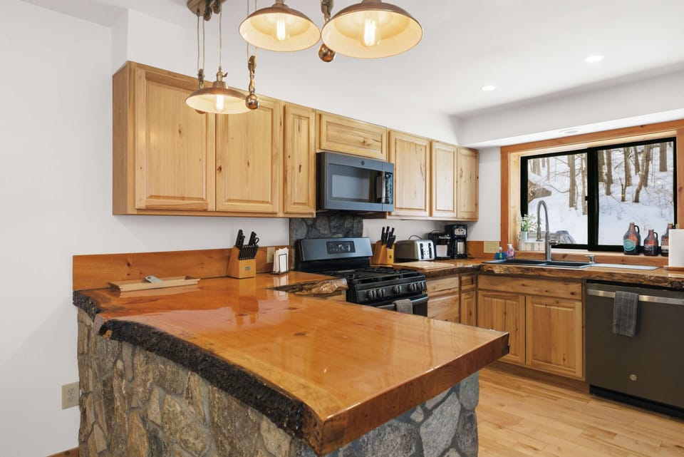 Fully equipped kitchen with live-edge countertops, stone island, and stainless steel appliances.
