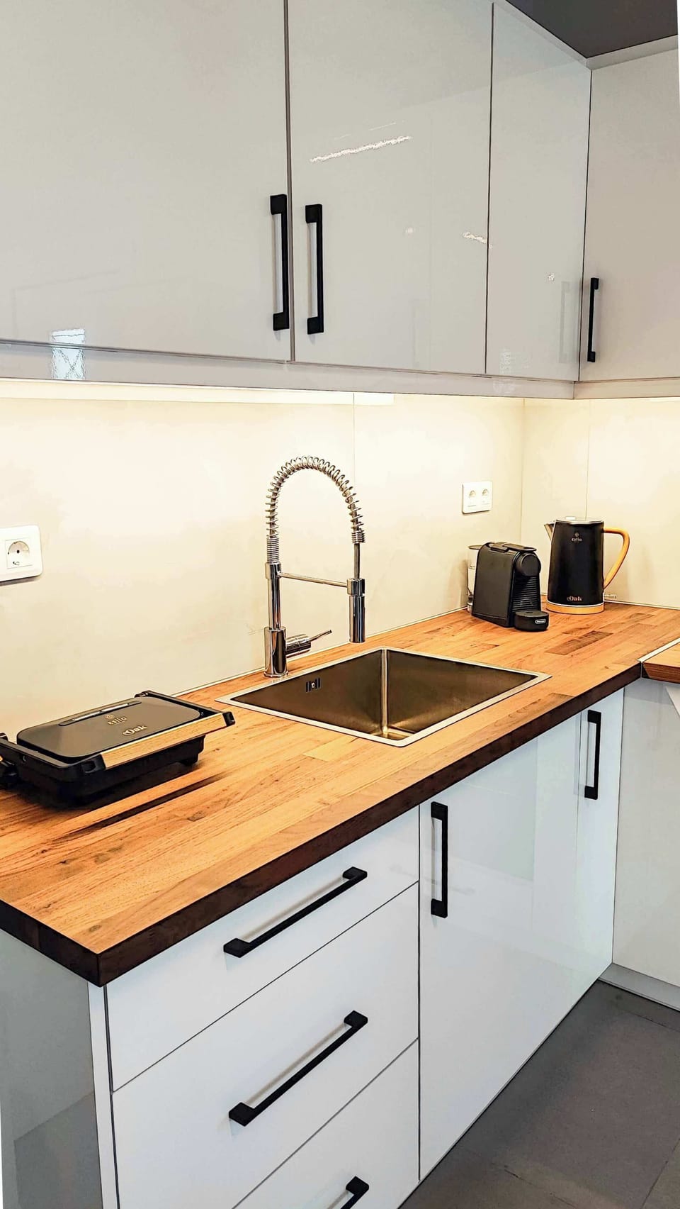 Modern kitchen with stovetop, oven, a kettle, a coffee machine, panini press and plenty of workspace. Fully equipped for preparing breakfasts, snacks, or full meals during your stay