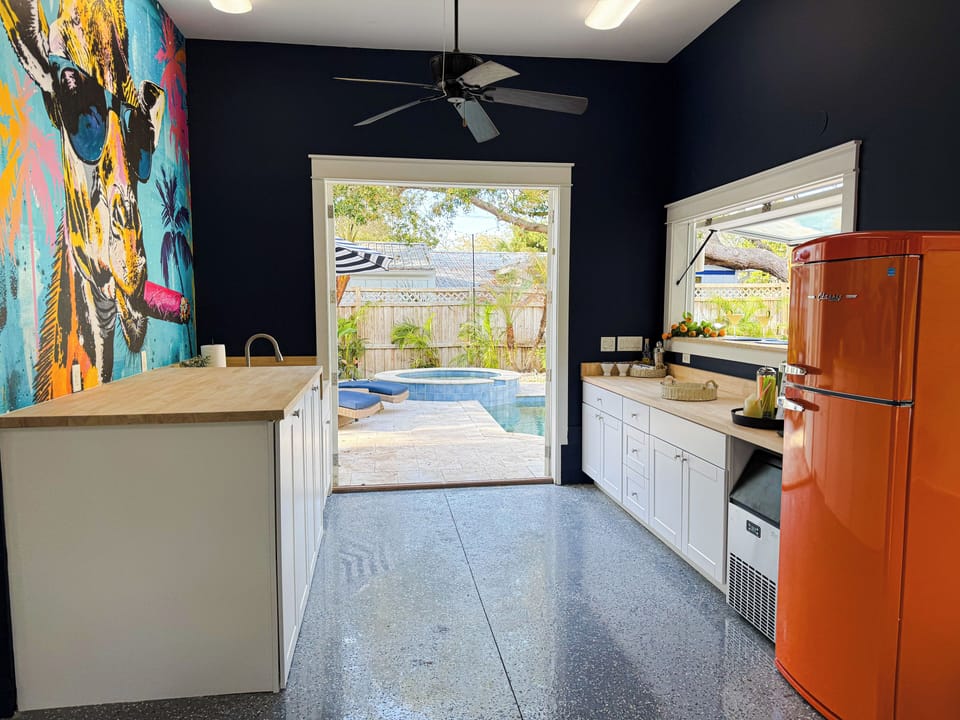 Poolside bar with flip-up window, retro inspired fridge, & easy access from the pool — perfect for drinks, snacks, and slushies. Enjoy the convenience of a second washer & dryer tucked away in this area—making longer trips even more comfortable.