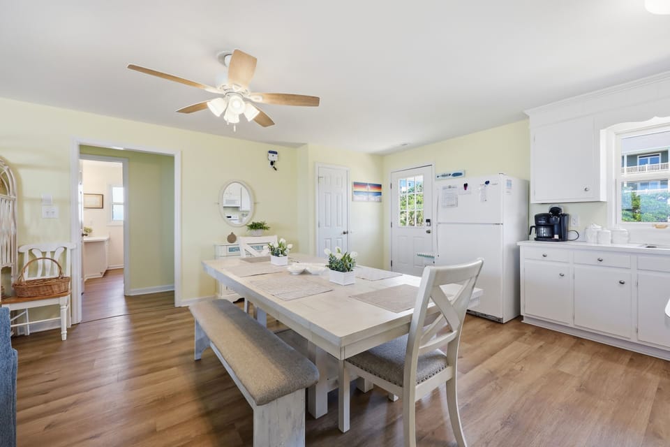 Gather around the welcoming dining table where morning coffee and home-cooked meals become cherished memories. Soft yellow walls and coastal touches create a cheerful, relaxed atmosphere for your group.