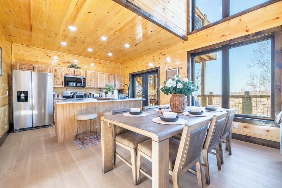 Your open-concept kitchen flows into a warm dining space, where meals become memories under soaring wood ceilings.