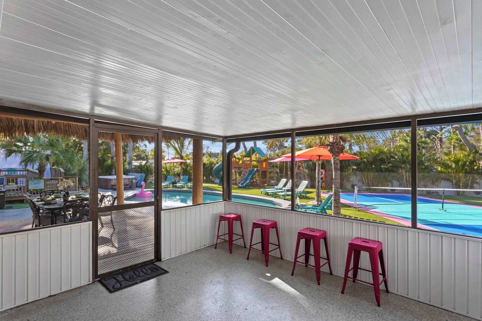 Screened-In Patio: Enjoy vibrant views of the pool and palm trees with friends in this sunlit retreat!