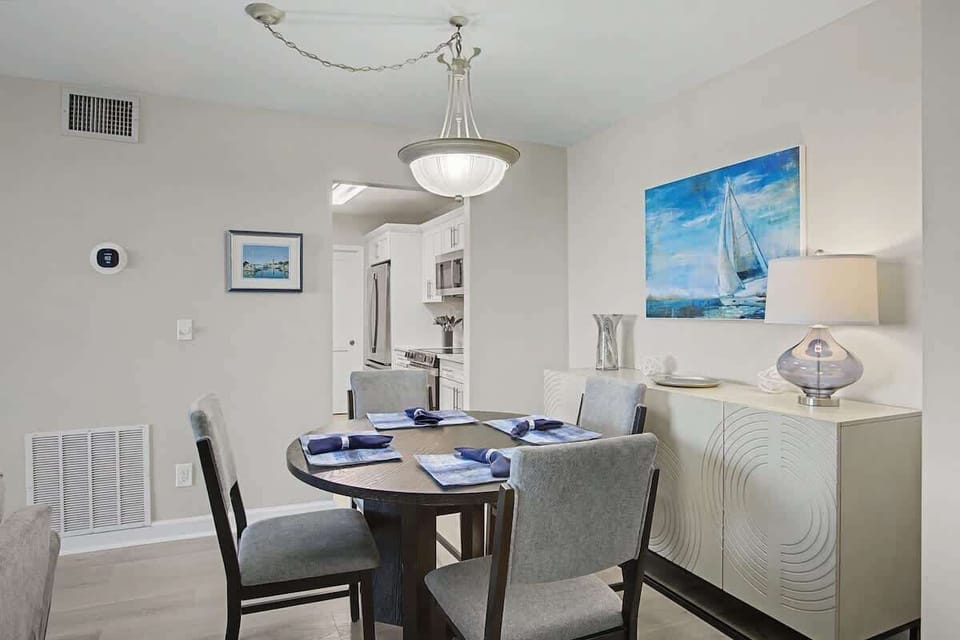 Gather around your elegant dining table where nautical artwork and stylish furnishings create the perfect setting for memorable meals together.