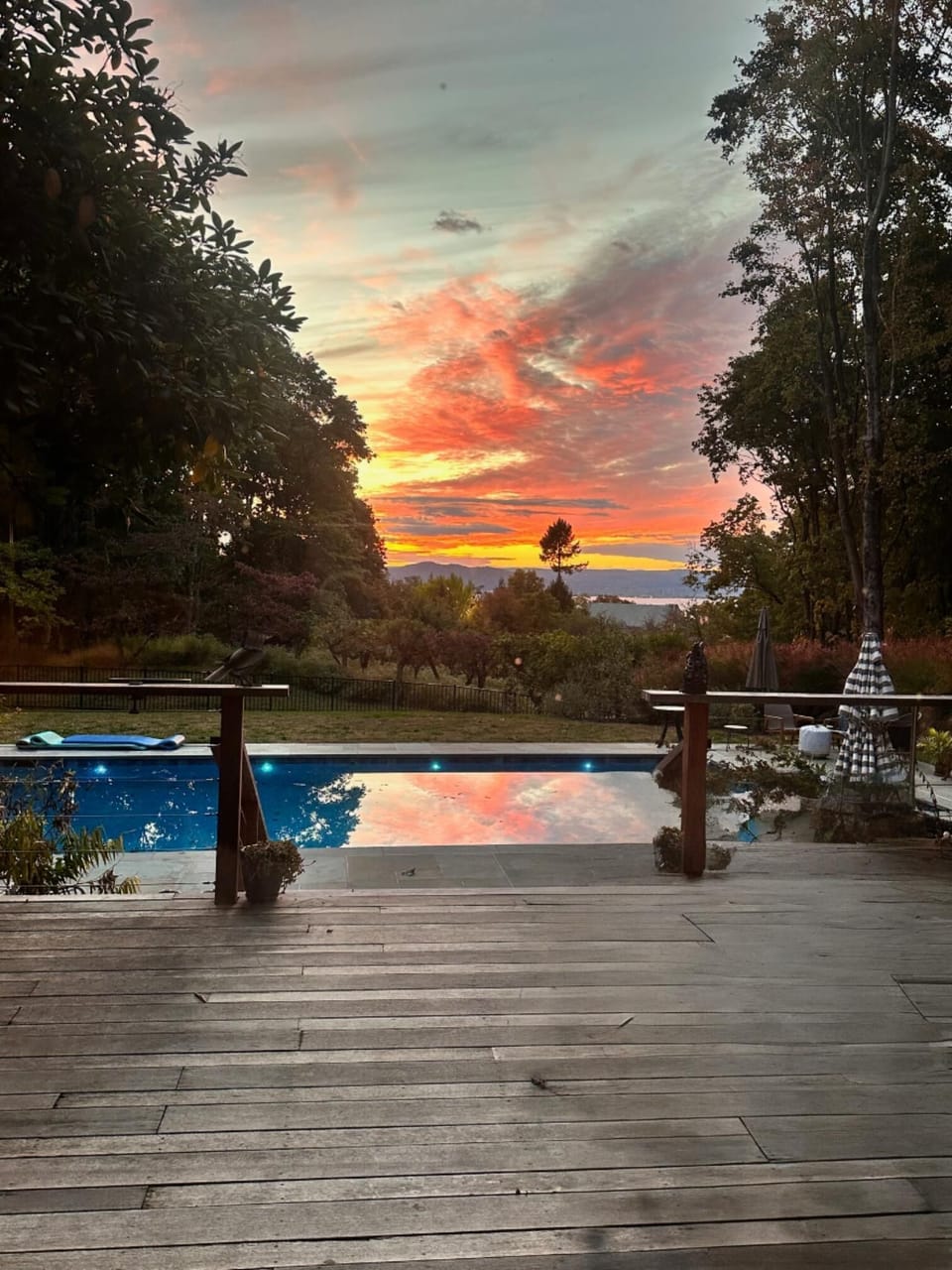 Sunset views over the distant Hudson River, by a private pool from a spacious wood deck oasis