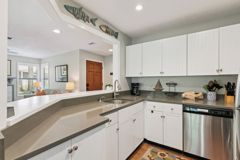 Whip up your favorite meals in this bright, fully equipped kitchen with sleek countertops and coastal touches. The open layout flows seamlessly into the living area—perfect for gathering.