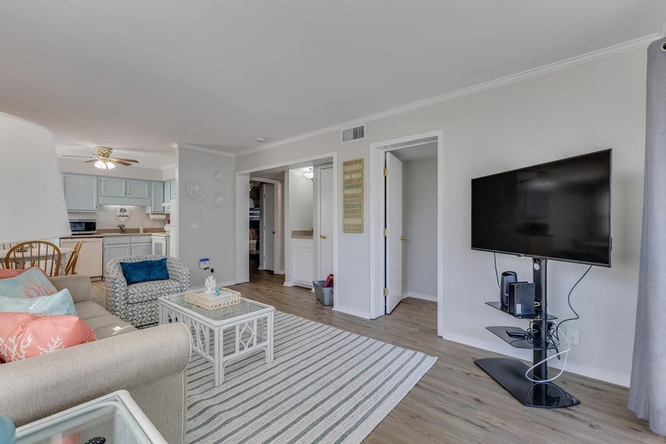Relax in your spacious living room with comfortable seating, coastal decor, and a large TV for entertainment after beach days.