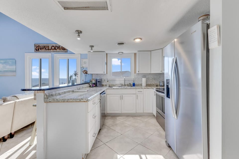 Your fully-equipped kitchen awaits with granite counters, stainless appliances, and stunning ocean views through every window.