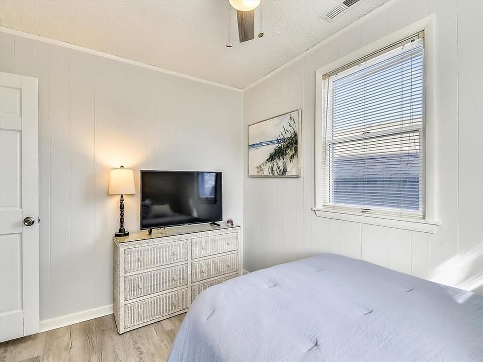 Cozy and bright, this tranquil bedroom features a comfortable bed, a stylish dresser, and a TV, perfect for unwinding after a day of exploration.