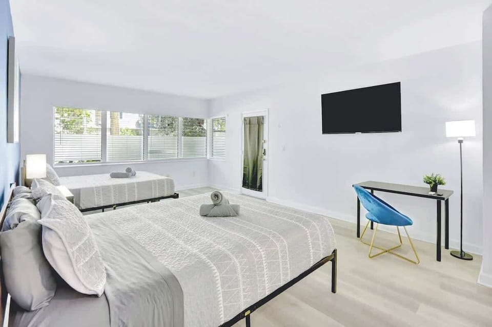 Open living area with 2 queen beds and a workspace under the TV.