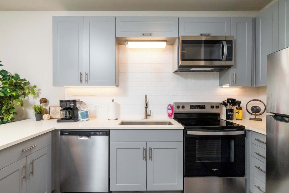 Compact kitchen fully stocked with all essentials and sleek stainless steel appliances—everything you need in a cozy space.