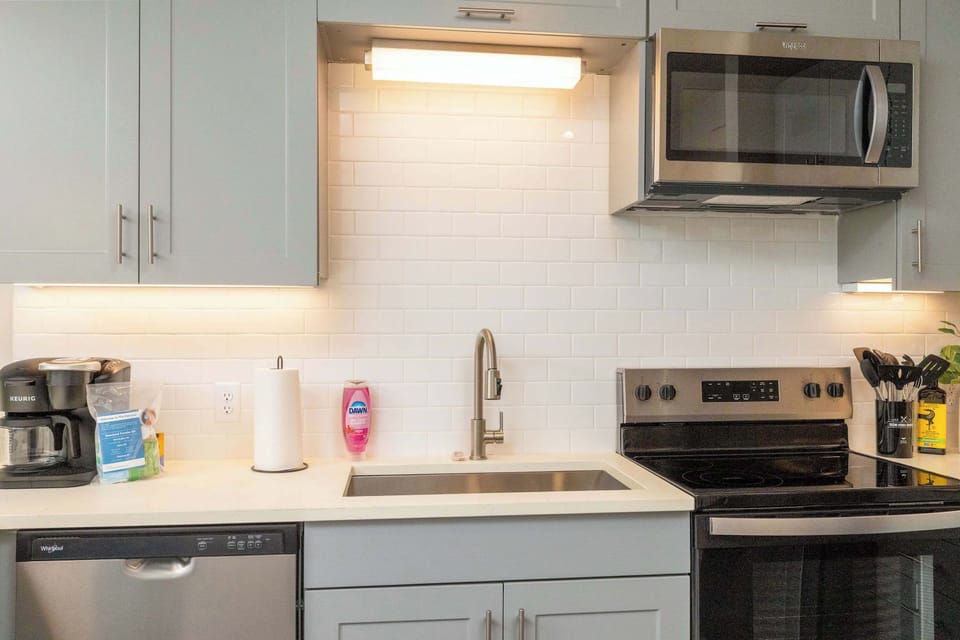 Compact kitchen fully stocked with all essentials and sleek stainless steel appliances—everything you need in a cozy space.