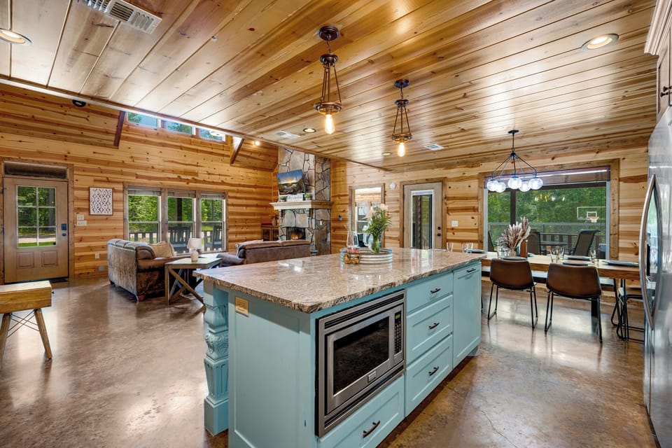 Spacious rustic-chic great room with granite island, fireplace, and deck views