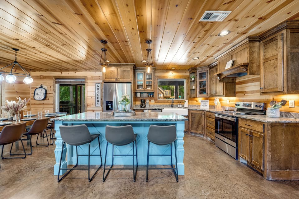 Rustic gourmet kitchen with large island, dining space, and warm wood charm