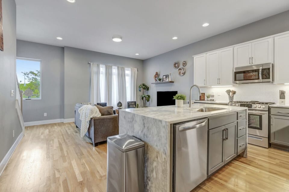 Modern open kitchen showcasing a marble waterfall island and premium stainless appliances.