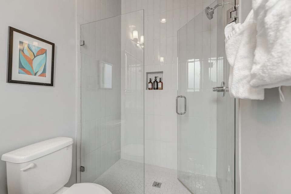 Modern glass-enclosed walk-in shower with built-in shelving.