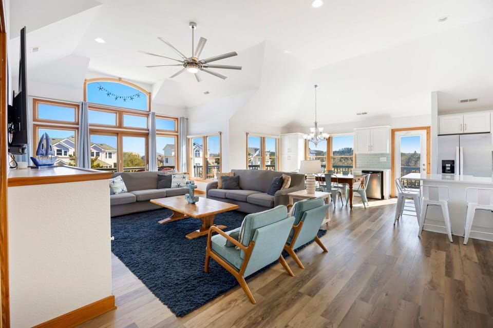The open-concept top-level living area is filled with natural light from large windows and coastal-inspired décor.