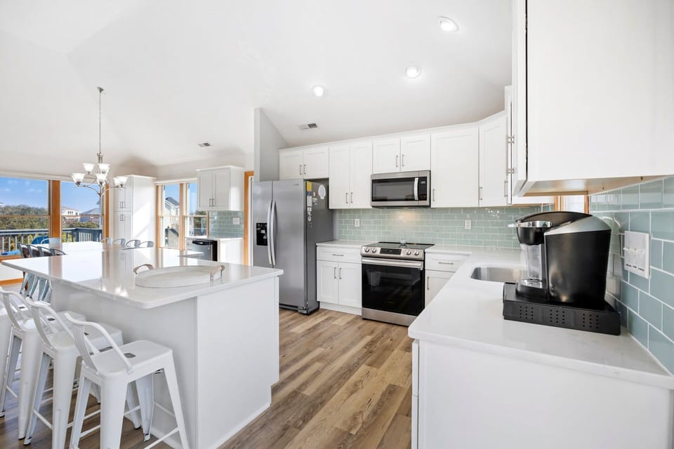The expansive kitchen features modern appliances, ample counter space, and two dishwashers for easy vacation cooking.