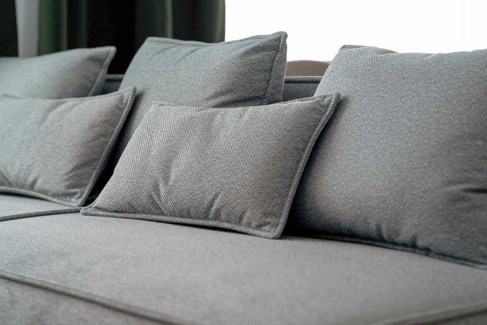 Soft grey sofa cushions arranged for comfort, emphasizing the inviting and relaxed character of the living space.