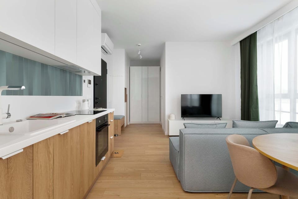 Modern kitchenette with white upper cabinets and wooden lower fronts, offering a clean design and practical layout for everyday cooking.