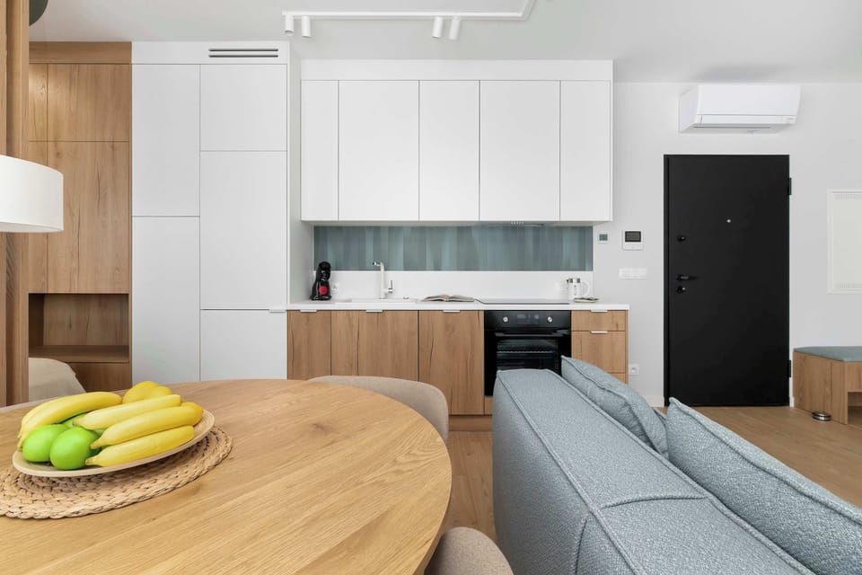 View from the dining area toward the kitchenette and sofa, presenting the harmonious flow of the entire studio interior.