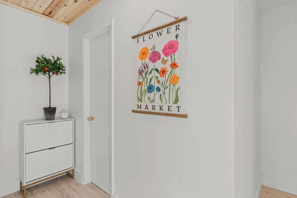 A bright "Flower Market" art print hangs in the clean, white entryway.