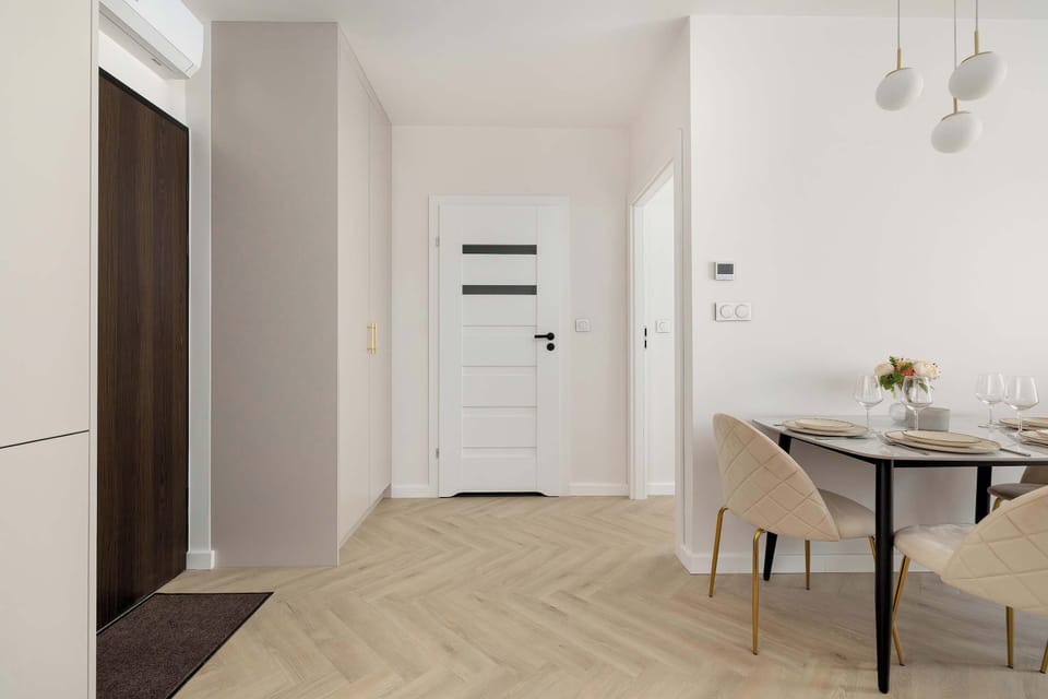 The view toward the entrance hall shows a built-in wardrobe and a white door, maintaining the apartment's organized and minimalist aesthetic.