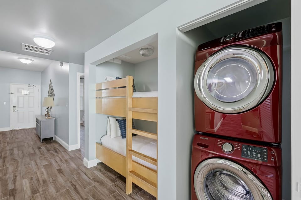 Modern laundry area with stacked washer and dryer next to a cozy bunk bed nook.
