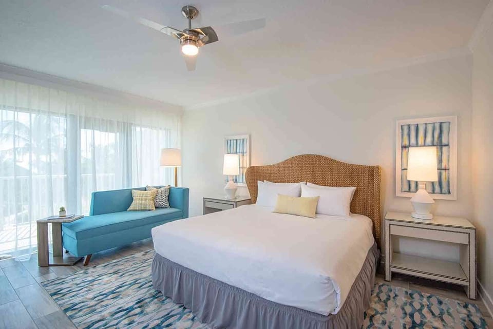 An oasis of tranquility, this elegantly designed bedroom blends coastal charm with modern comfort, complete with natural light filtering through sheer curtains and a restful color palette.
