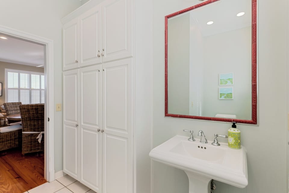 Step into your elegant powder room with classic pedestal sink and ample storage in custom cabinetry.