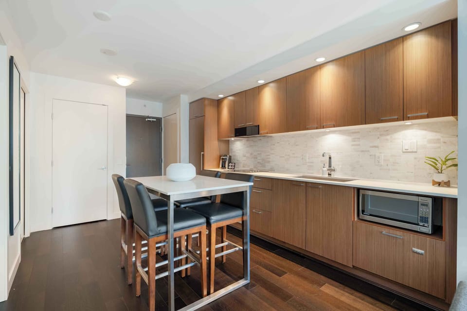 Fully equipped modern kitchen with full-size appliances, sleek cabinetry, and a dining table for in-suite meals.