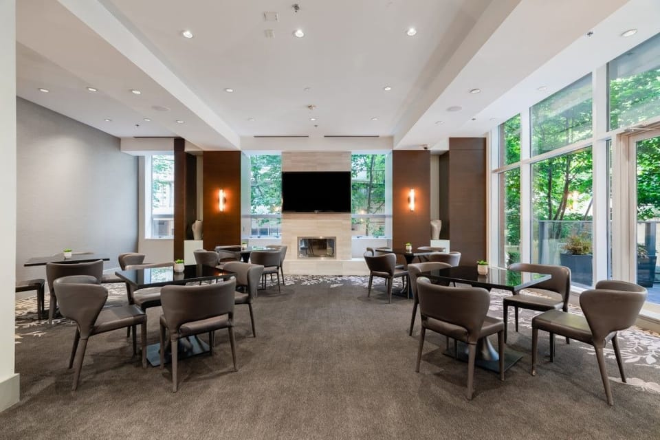 A cozy gathering space showcases minimalist furnishings, a contemporary fireplace, and large windows that blur the line between indoor comfort and outdoor serenity.