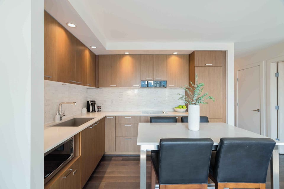 Modern studio kitchen with sleek cabinetry, stone countertops, and bar seating for casual meals