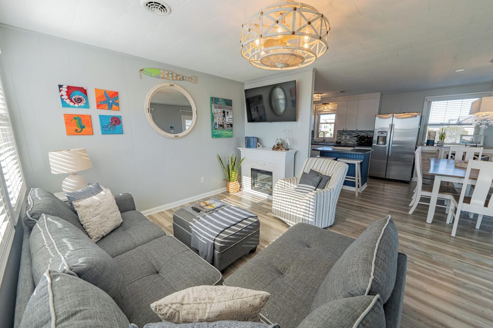 Airy coastal living space with fireplace, island kitchen, and dining.
